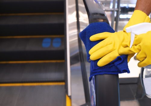 Staff cleaning the escalator hand rail in department store to prevent the pandemic Coronavirus